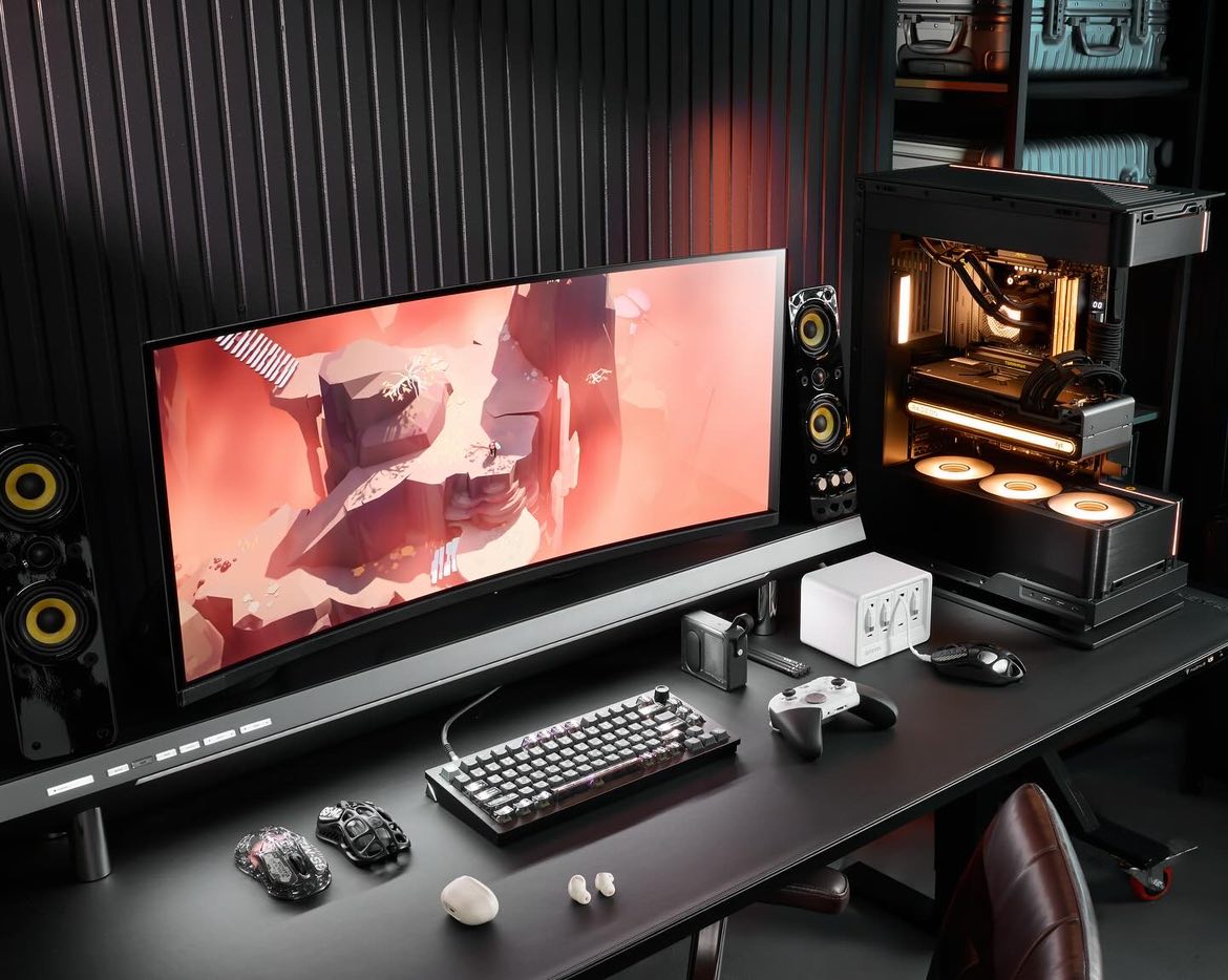 A high-tech gaming desk featuring a curved monitor displaying a game, paired with a mechanical keyboard, custom gaming mouse, and a game controller.